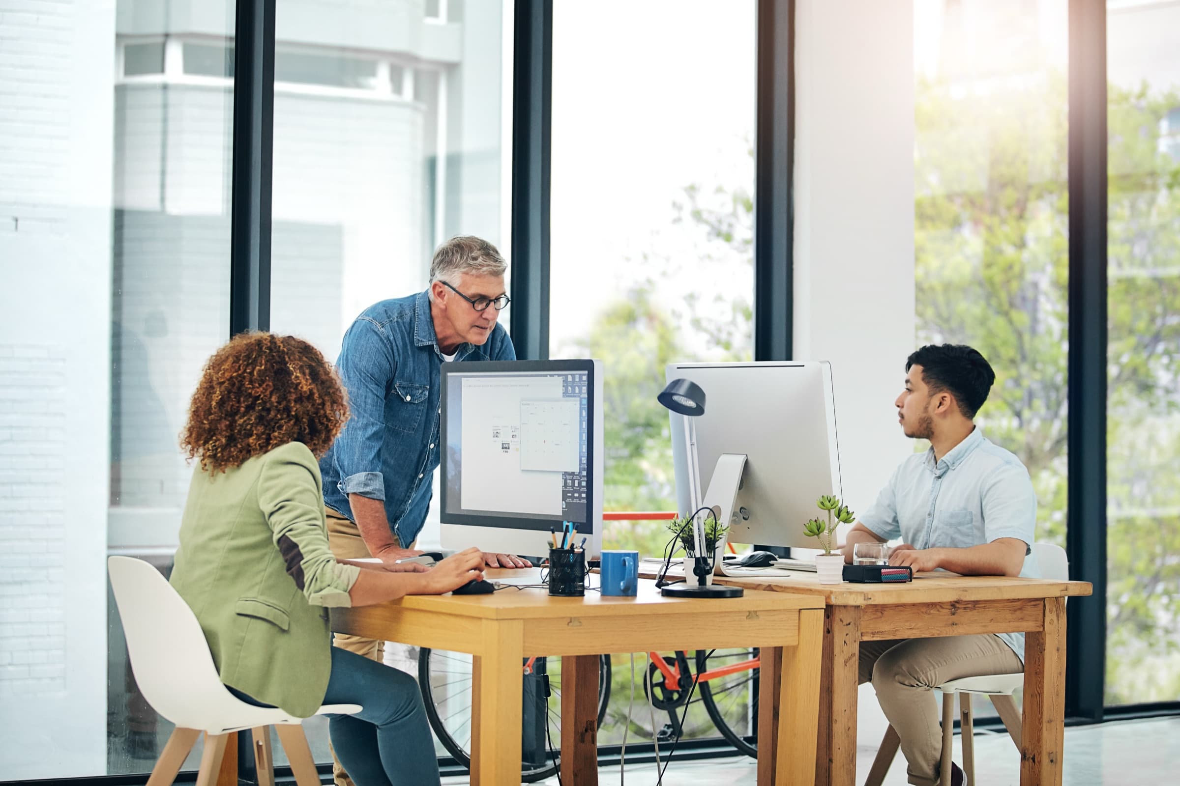 Small support team coaching at a computer in an open coworking space